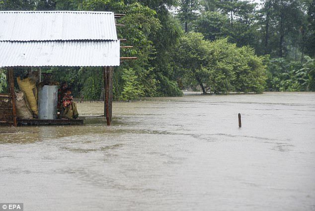 A woman and her child appear stranded as the water rises around their home in the Saptari district