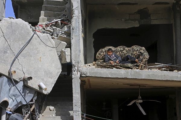Mohammed Keferna, 14, sits on a couch in his family's building that was damaged by Israeli strikes during last summer's Israel-Hamas war, in Beit Hanoun, northern Gaza Strip