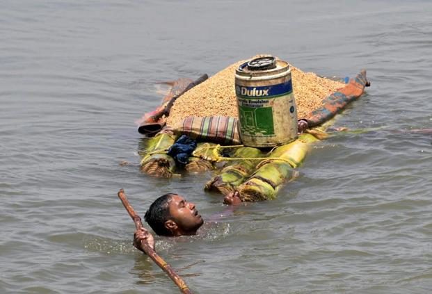 A villager carries grains on a raft as he shifts from a flooded village in Araria