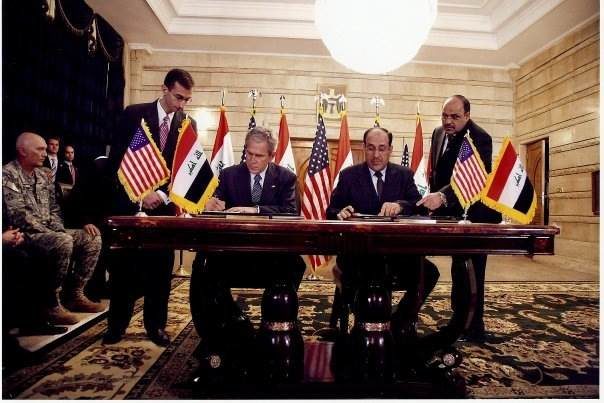 Ali Khedery, pictured far left, watches as U.S. President George W. Bush, sings an agreement with Iraqi Prime Minister Nouri al-Maliki