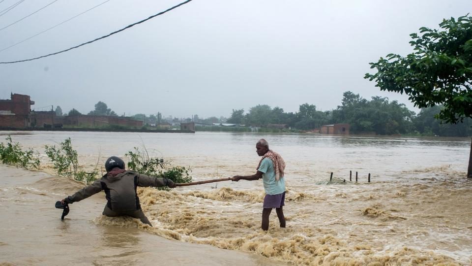 Nepali residents help each other cross a flooded road at Birgunj Parsa district