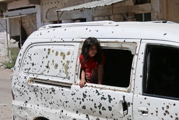 A girl looks out from a bullet-riddled bus in a rebel-held part of the southern city of Deraa