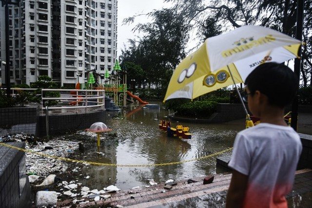 A young child looks at a flooded playground and marine debris after heavy winds and rains brought on by Typhoon Hato in Hong Kong on August 23, 2017.