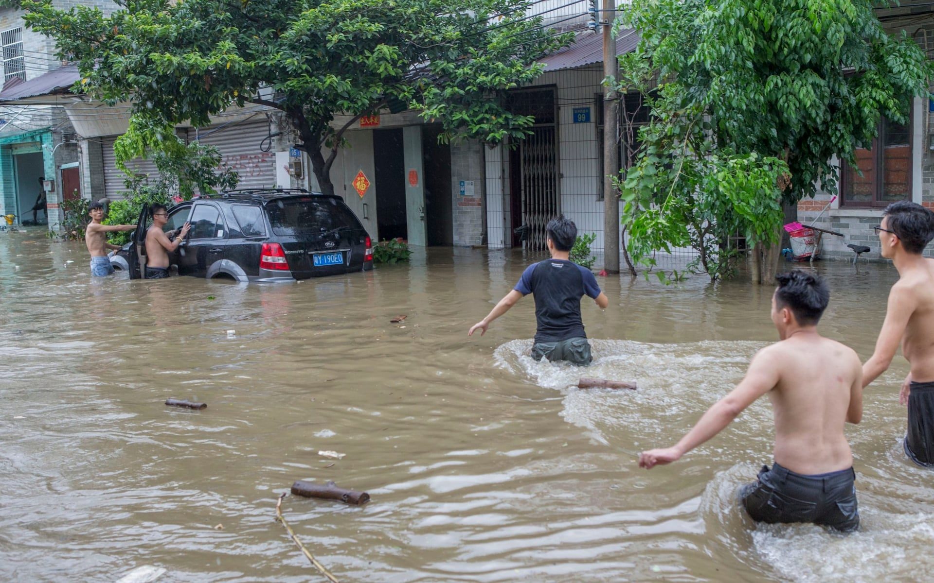 People walk to a vehicle trapped in the flooding caused by Typhoon Hato and the astronomical tide on August 23, 2017 in Guangzhou, China