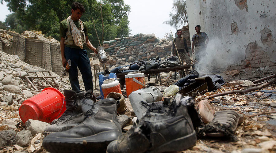 Afghan policemen inspect a destroyed police checkpoint