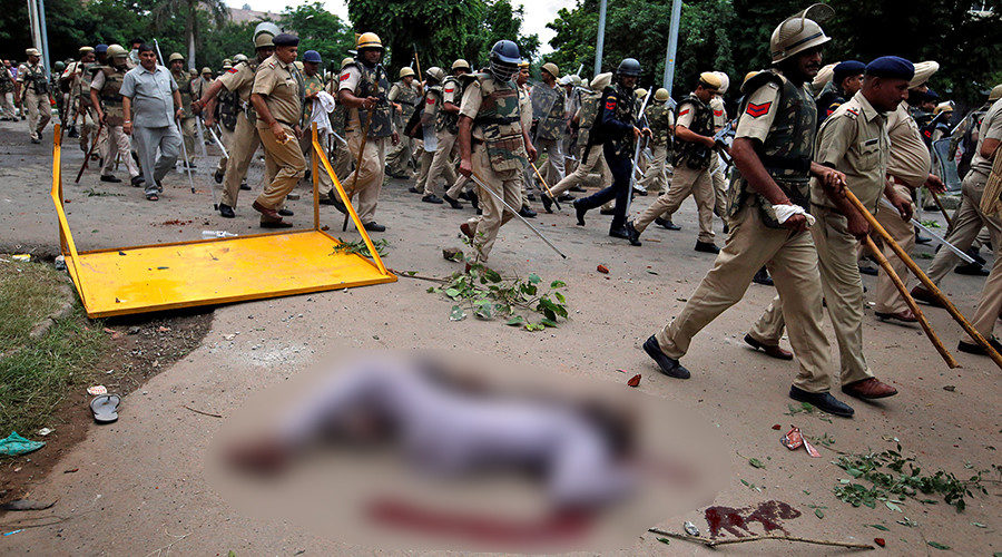 Security forces march past the body of a man killed during violence in Panchkula, India=
