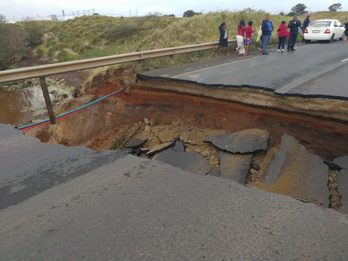 Sphiwe Mbense's vehicle can be seen in the background after it nearly fell into the sinkhole with him and his girlfriend inside.