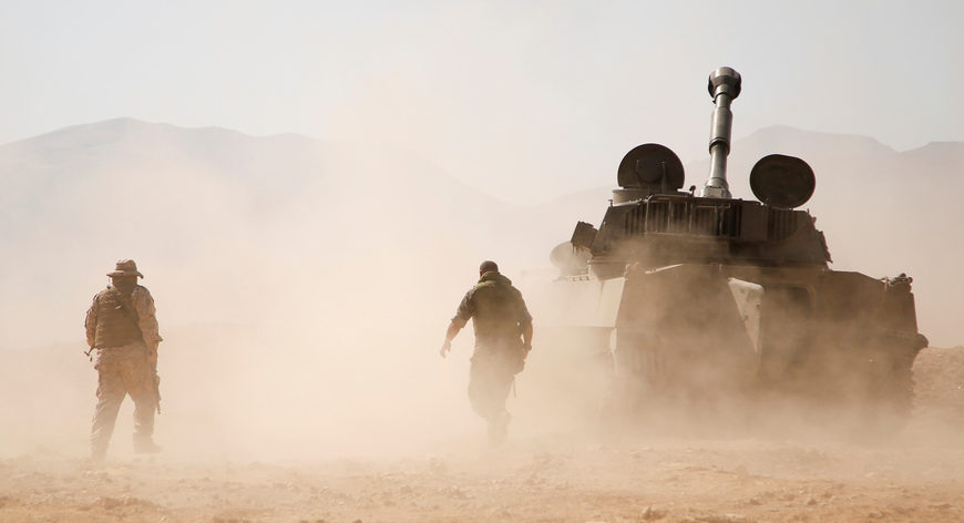 Hezbollah fighters walk behind a tank in western Qalamoun, Syria