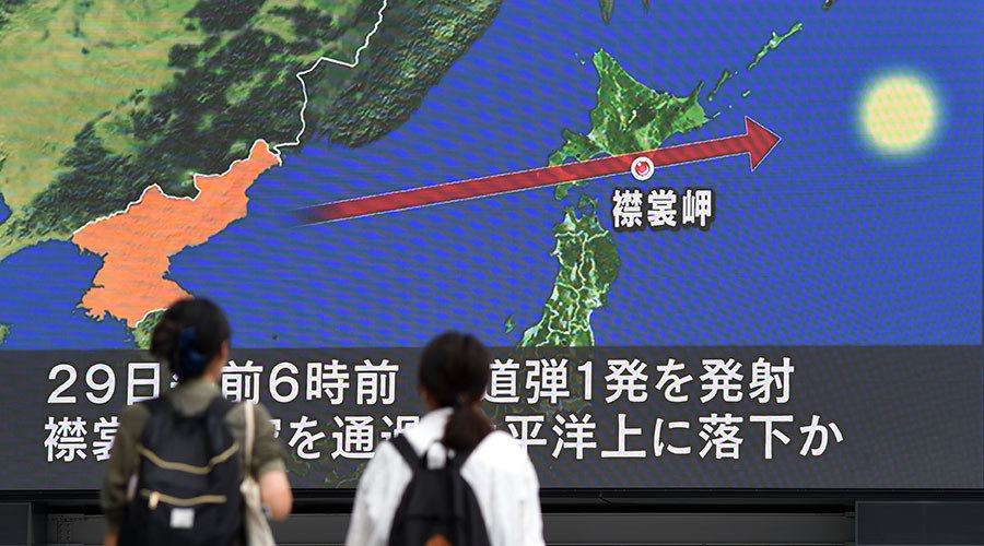 Pedestrians watch the news on a huge screen displaying a map of Japan (R) and the Korean Peninsula, in Tokyo on August 29, 2017.