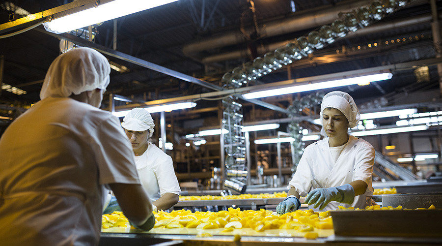 Workers select sliced peaches to place into metal cans