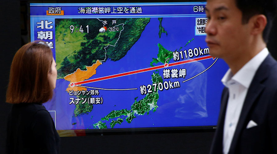 Pedestrians walk past a TV set showing news about North Korea's missile launch
