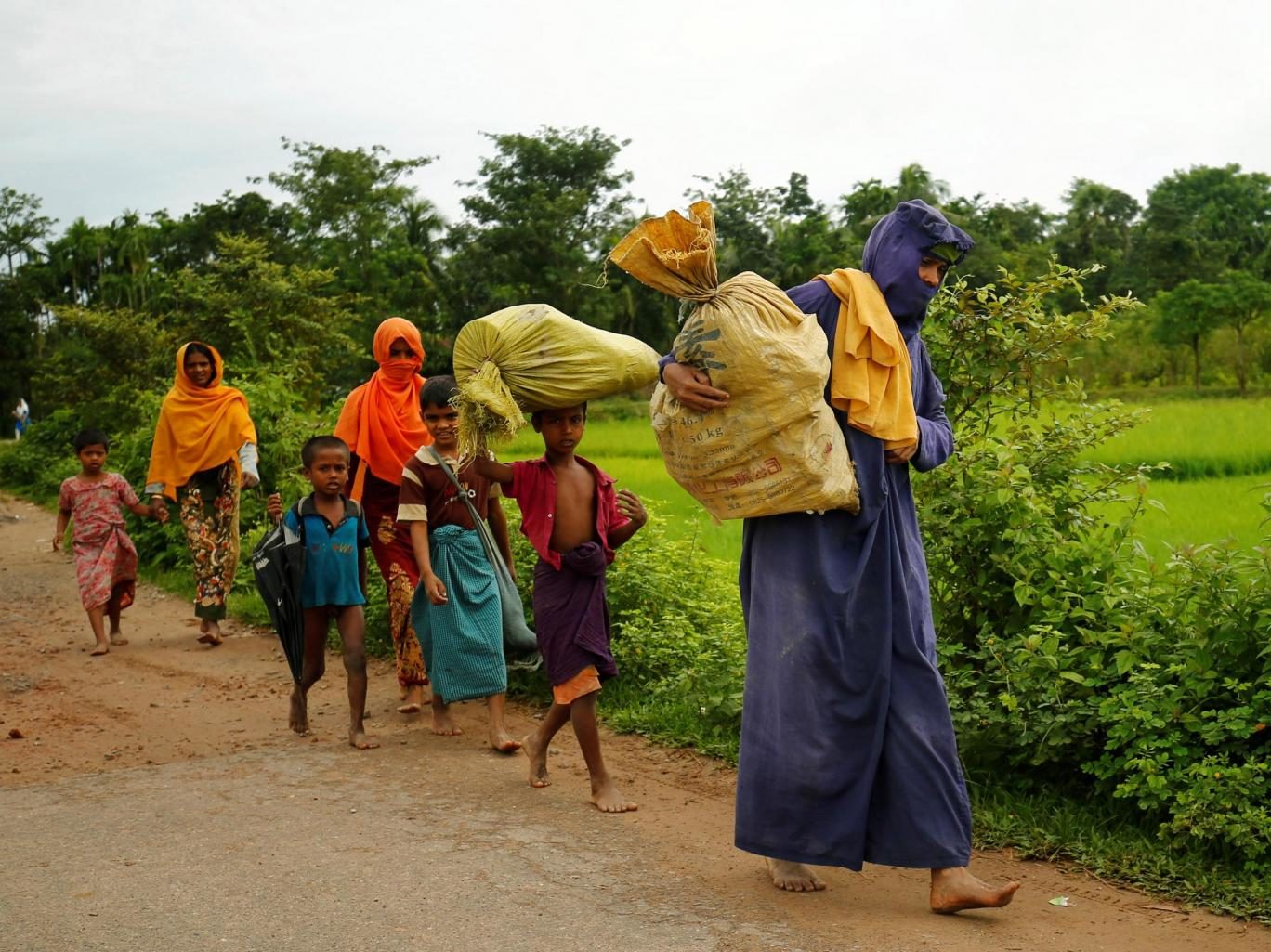 Rohingyas walk along the road to reach to the refugee camp