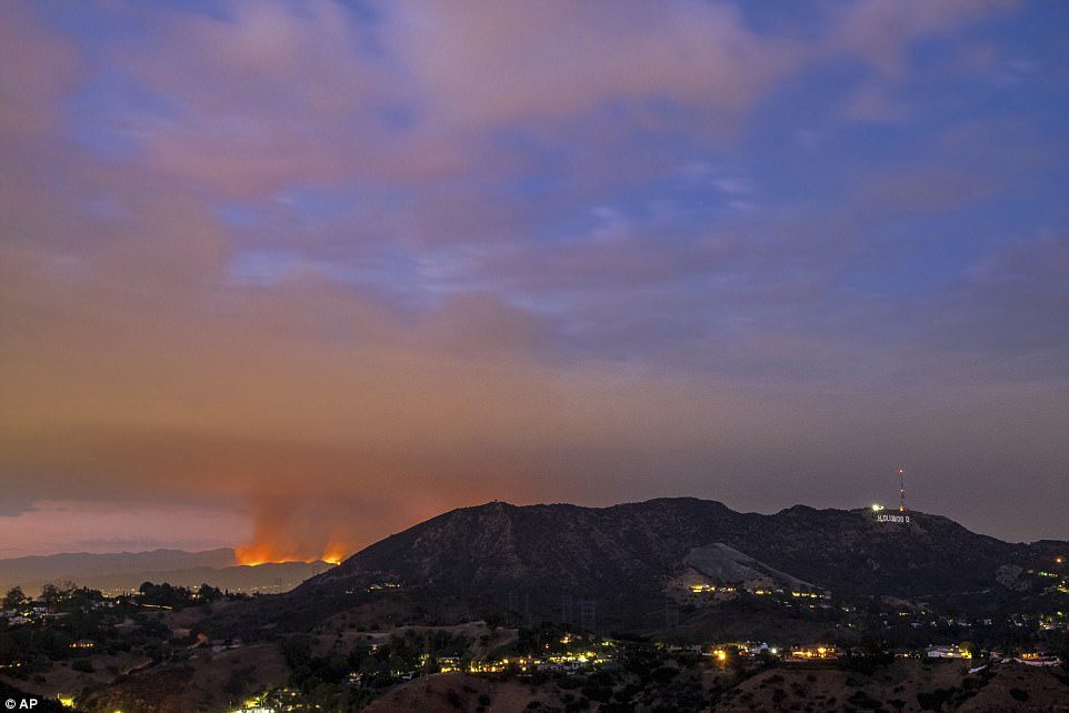 La Tuna Fire rages behind the Hollywood Hills on Friday, with the famed Hollywood sign in the front, right
