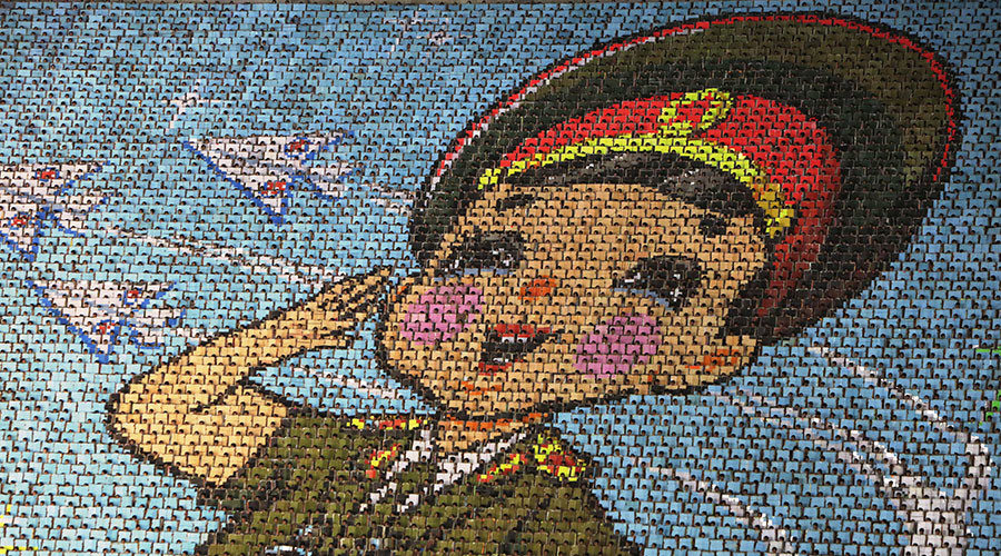 North Korean students use different colored cardboard to form a picture of a child in uniform, Pyongyang