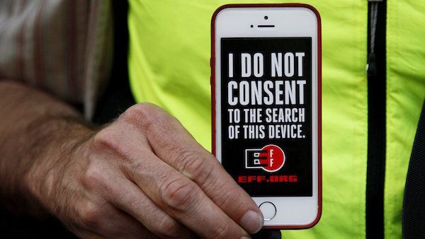man holds up his iPhone during a rally in support of data privacy
