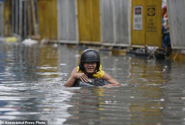 A resident uses a makeshift floater as he crosses a flooded street in Manila, Philippines on Tuesday, Sept. 12, 2017.