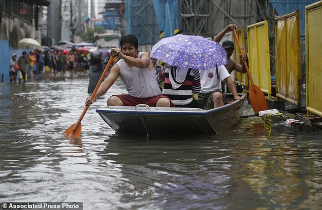 Filipinos ride a boat as they cross a flooded street in Manila, Philippines, Tuesday, Sept. 12, 2017.