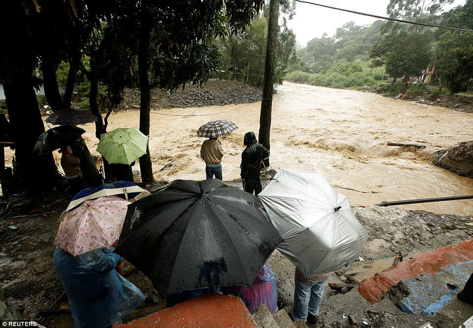 Surging waters: People look at the Tiribi river flooded after heavy rains by Tropical Storm Nate in San Jose, Costa Rica