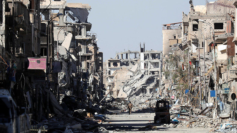 A fighter of Syrian Democratic Forces stands amidst the ruins