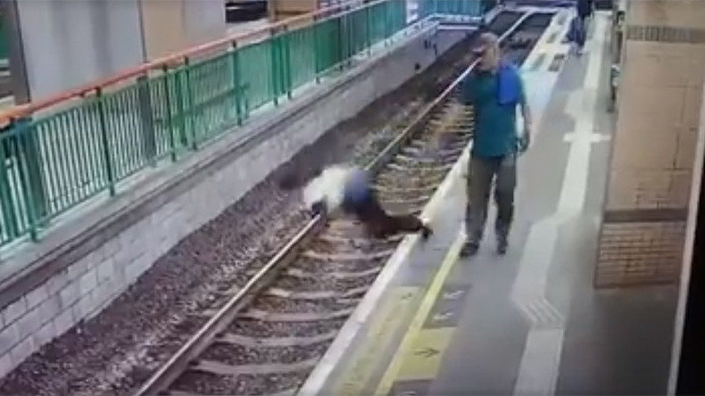 man pushing woman on train track