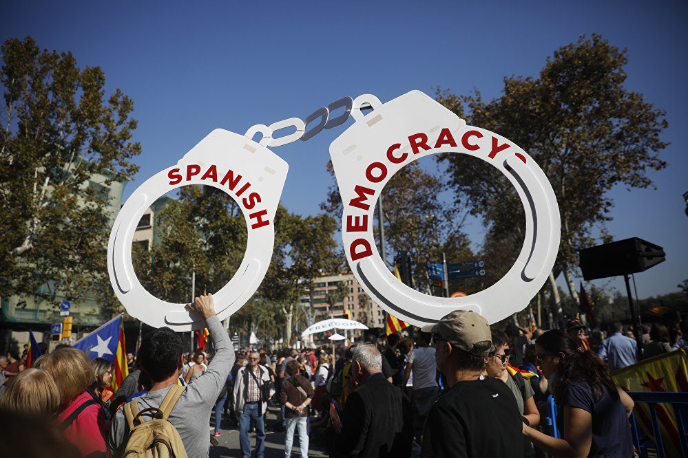 Protesters hold fake handcuffs as they take part a rally outside the Catalan parliament in Barcelona, Spain, Friday, Oct. 27, 2017.