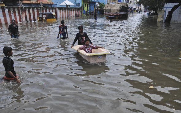A boy pushes another in a bathtub in a waterlogged street in Chennai, India, on Friday, Nov. 3, 2017.