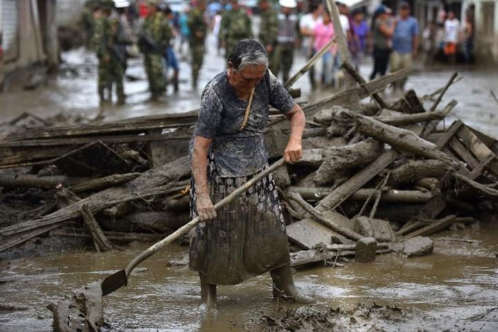A woman cleans a street affected by the flooding of La Paila river in the municipality