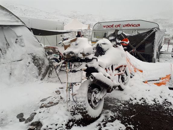 Blankets of snow covers motorbike.