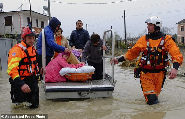 Authorities help a family evacuate from their home after heavy rainfall in the village of Hasan, about 25 kilometers (15 miles) north of Tirana, Friday, Dec. 1, 2017.