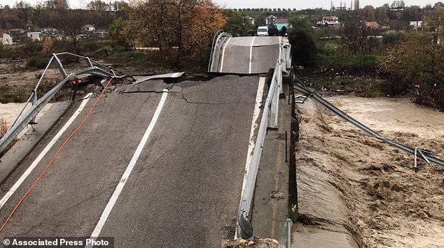 Local residents inspect a collapsed bridge at the entrance of their village Mamuras, northern Albania, Friday, Dec. 1, 2017.