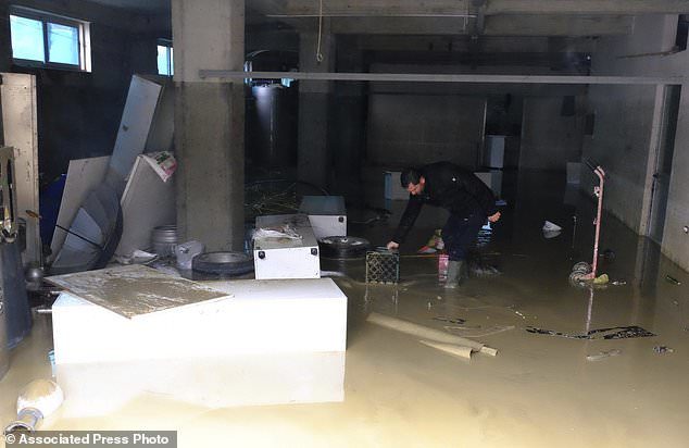 A man tries to clean his flooded shop after heavy rainfalls in Tirana, Friday, Dec. 1, 2017.