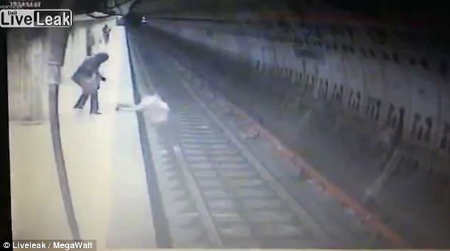 The victim attempts to climb back on to the platform as her attacker kicks at her hands. She was not able to escape before the train entered the station