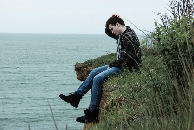 Click to enlarge man sitting by ocean