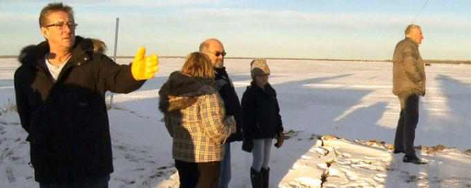 Residents examine a crack in the ground after a mysterious bang in Alberta Beach, Alta., Tuesday, Jan. 2, 2018