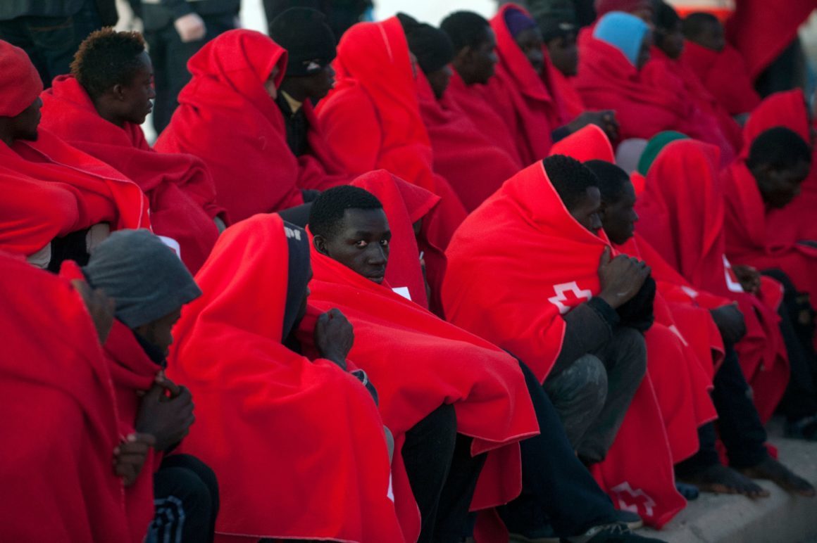Migrants keep warm with Red Cross blankets after arriving aboard a coast guard boat at Malaga's harbour on December 7, 2017