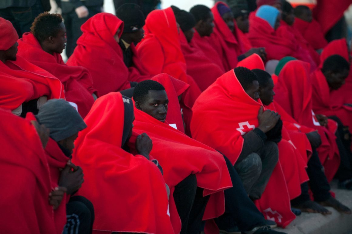 Click to enlarge Migrants keep warm with Red Cross blankets after arriving aboard a coast guard boat at Malaga's harbour on December 7, 2017