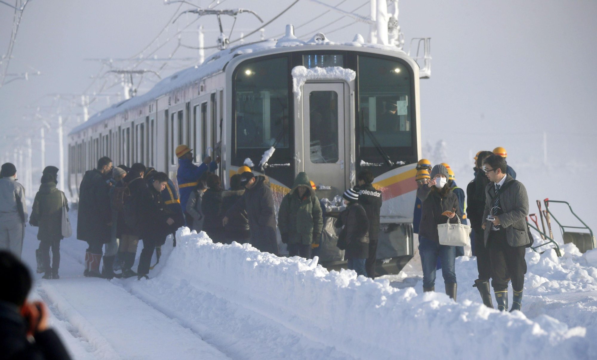 Passengers on Friday walk out of a train on East Japan Railway Co.'s Shinetsu Line, where they spent the night after being stranded