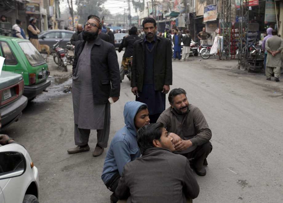 People stand outside their shops after a severe earthquake is felt in Rawalpindi, Pakistan, Wednesday, Jan. 31, 2018.