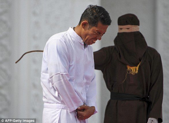 Click to enlarge Jono Simbolon (front), an Indonesian Christian, grimaces in pain as he is flogged in front of a crowd outside a mosque in Banda Aceh, Aceh province, on January 19, 2018
