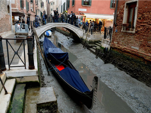 A gondola is seen tied up in Venice, near the Rialto bridge, on January 31, 2018, as exceptionally low tides have drained the lagoon city.