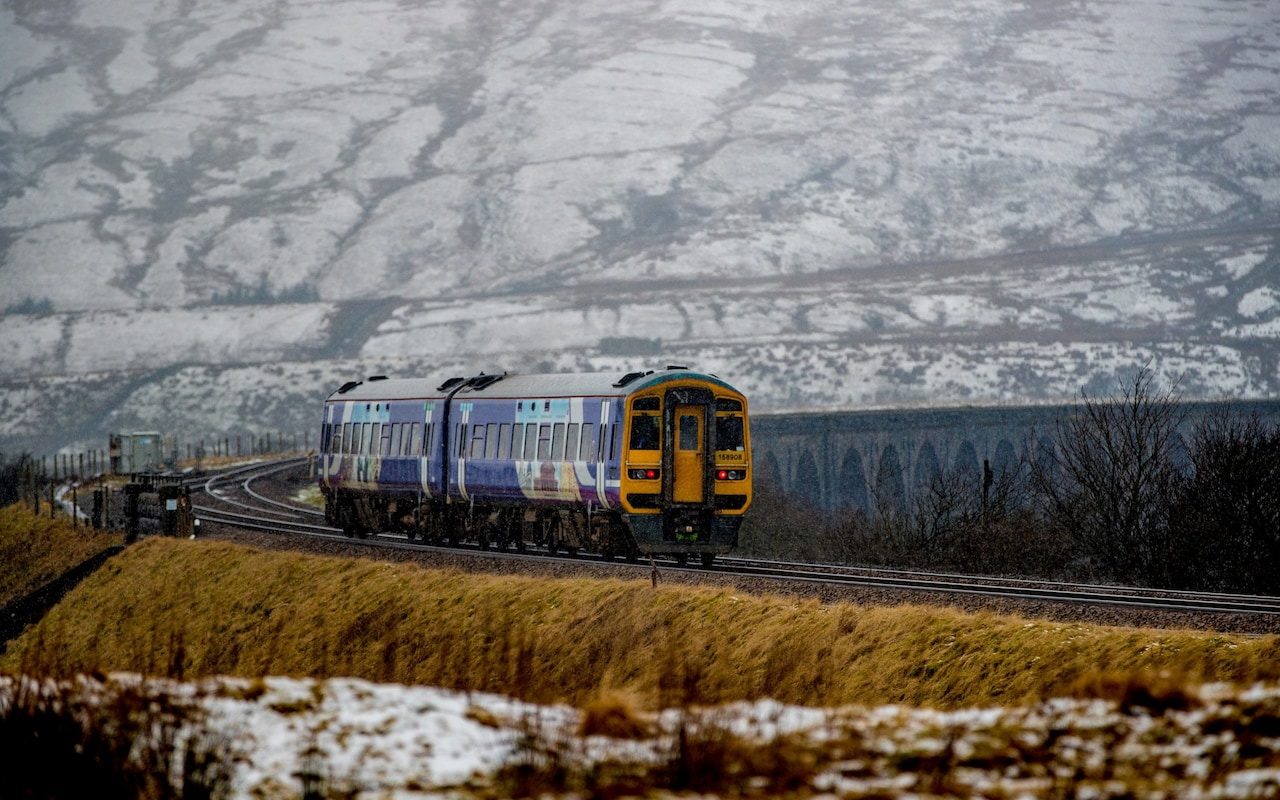 A steam train passes over Ribblehead Viaduct in North Yorkshire as snow covers the landscape