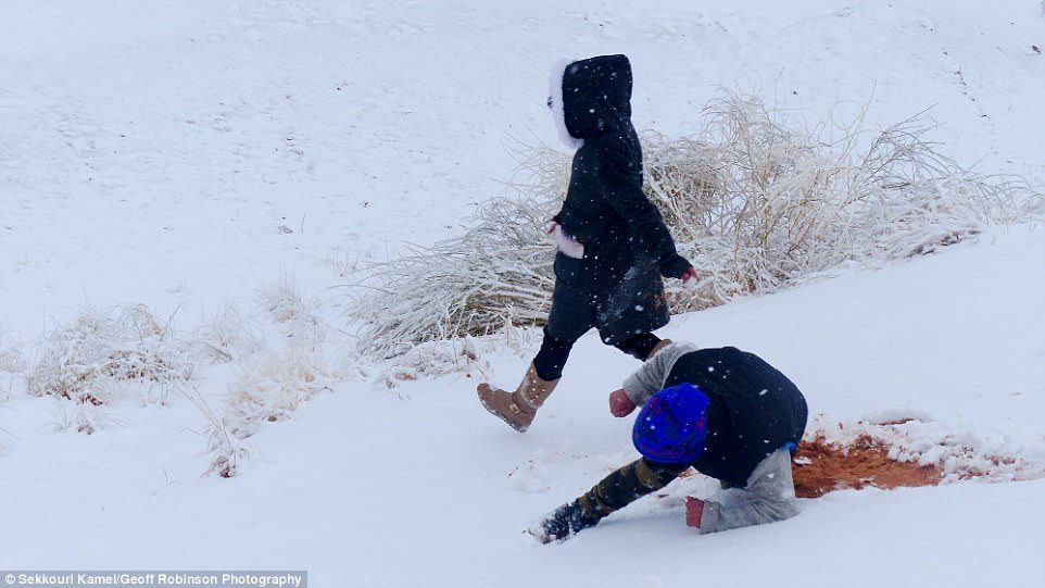 Click to enlarge Snowday! A child takes a tumble in the snow, exposing the red sand hidden underneath it