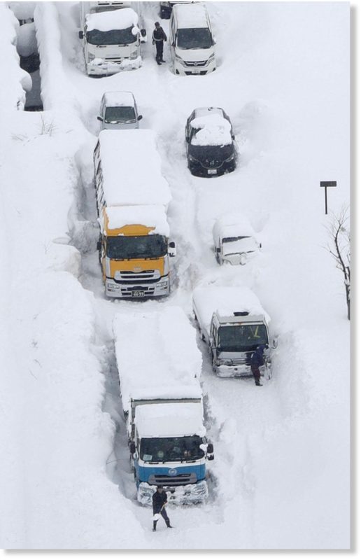 An aerial photo shows cars and trucks buried in snow and stranded on Route 8 in Sakai, Fukui Prefecture, on Wednesday.