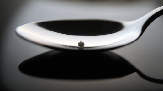 A homeopathic globule held on a teaspoon.