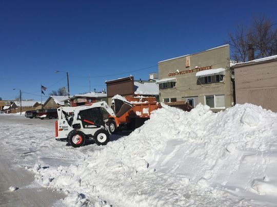 Tim LaBuea uses a Bobcat to load snow onto a truck driven by Larry Geyer in Big Sandy.