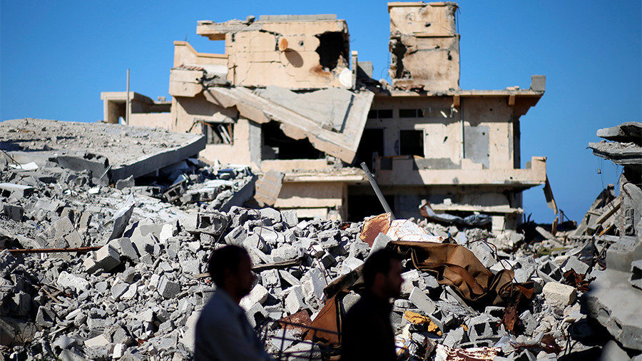 Men walk past the ruins of a building