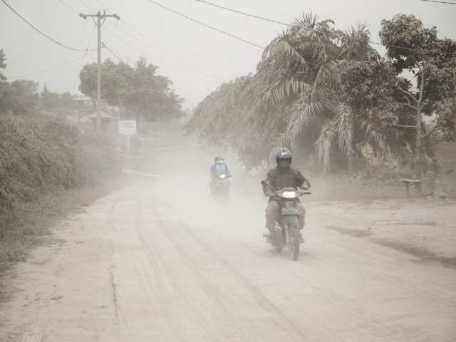 Click to enlarge Motorists ride on a road covered in volcanic ash