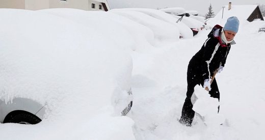 A woman removes the snow that blocks her car in Saint-Chaffrey as winter weather bringing snow and freezing temperatures continued in France on Thursday.