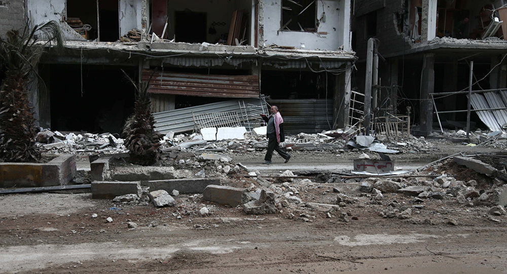 A Syrian man walks past destroyed buildings