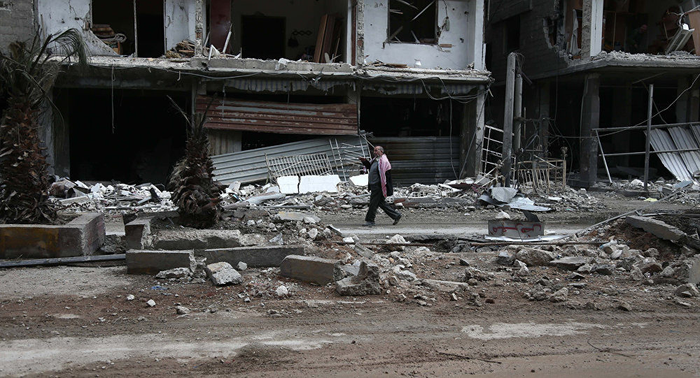 Click to enlarge A Syrian man walks past destroyed buildings
